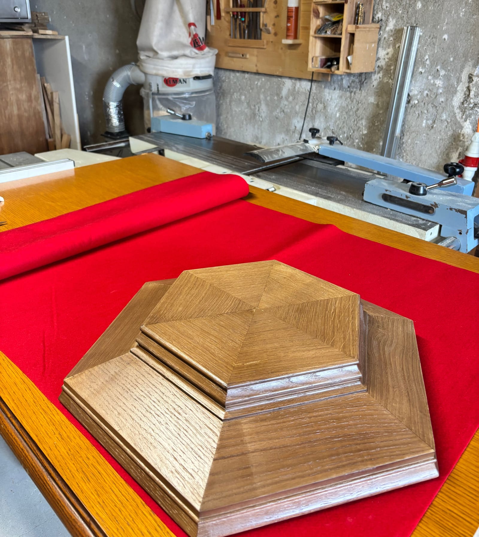 Pièce hexagonale en bois sur l'établi, tissu rouge.